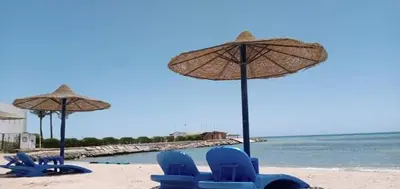a group of blue chairs and umbrellas on a beach at سيسيليا اتش in Hurghada