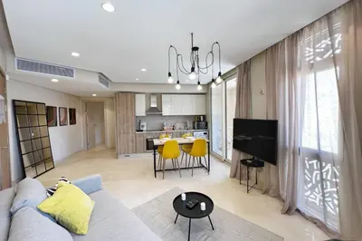 a living room and kitchen with a blue couch and yellow chairs at Enticing & Earthy 1 BDR Mangroovy Free Pool & Beach Access in Hurghada