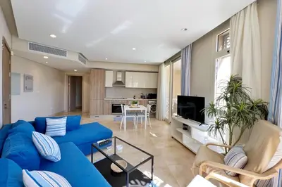 a living room with a blue couch and a kitchen at Proper & Plush 1 BDR Mangroovy Free Pool & Beach Access in Hurghada