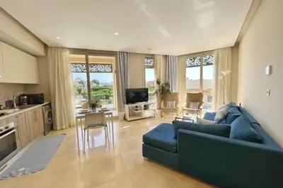 a living room with a blue couch and a kitchen at Proper & Plush 1 BDR Mangroovy Free Pool & Beach Access in Hurghada