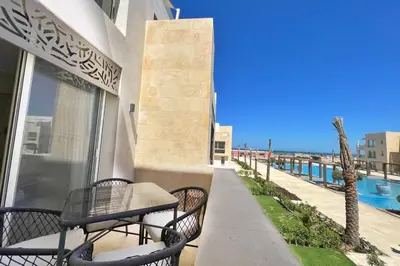 a patio with a table and chairs on a balcony at Modern & Mellow 1 BDR Mangroovy Free Beach & Pool Access in Hurghada