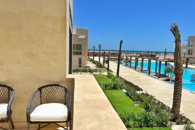 a patio with chairs and a view of the ocean at Modern & Mellow 1 BDR Mangroovy Free Beach & Pool Access in Hurghada