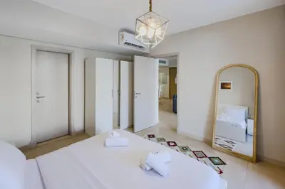 a bedroom with a large white bed and a mirror at Roomy & Relaxed 1BDR Mangroovy Free Beach & Pool in Hurghada