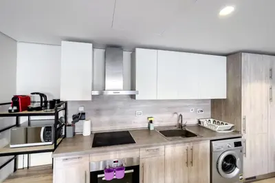 a kitchen with white cabinets and a sink and a dishwasher at Roomy & Relaxed 1BDR Mangroovy Free Beach & Pool in Hurghada