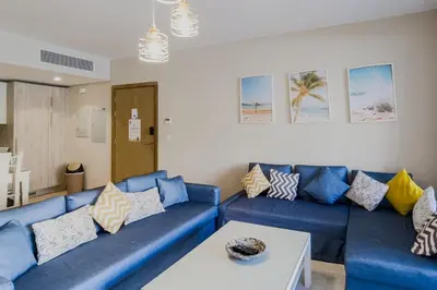 a living room with a blue couch and a table at Roomy & Relaxed 1BDR Mangroovy Free Beach & Pool in Hurghada