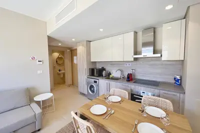 a kitchen and living room with a wooden table and chairs at Seascape 1 BDR Mangroovy Pool & Sea View in Hurghada