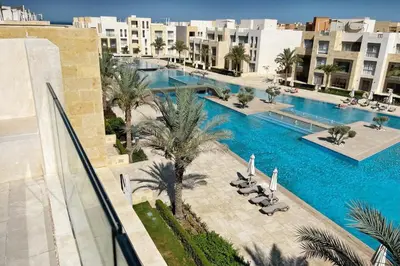 an overhead view of a swimming pool with palm trees and buildings at Spectacular & Soaring 2 BDR w Private Rooftop Jacuzzi & Beach Access in Hurghada