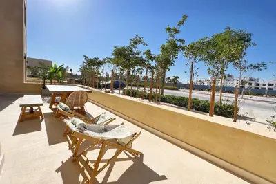 a balcony with chairs and a table and trees at Sparky & Summery 2 BDR Mangroovy Free Beach & Pool Access in Hurghada