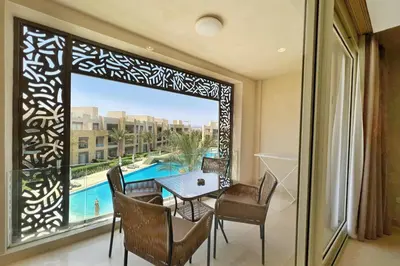 a balcony with a table and chairs and a large window at Radiant & Ravishing 2 BDR Mangroovy Free Beach & Pool Access in Hurghada