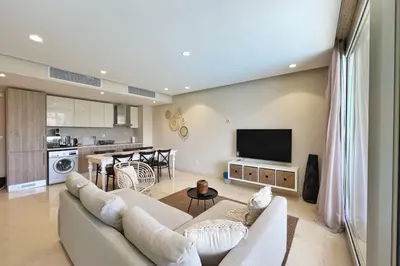 a living room with a white couch and a kitchen at Radiant & Ravishing 2 BDR Mangroovy Free Beach & Pool Access in Hurghada