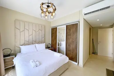 a bedroom with a large white bed and a chandelier at Charming 2BDR w Sea & Pool View Free Beach & Pool Access in Hurghada