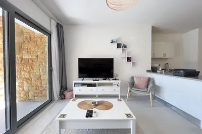 a living room with a tv and a table at Lagoonfront Easy 1BDR Swan Lake El Gouna in Hurghada