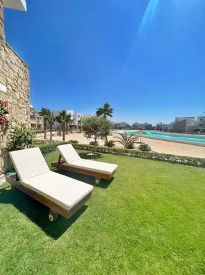 two beds on the grass next to a beach at Lagoonfront Easy 1BDR Swan Lake El Gouna in Hurghada
