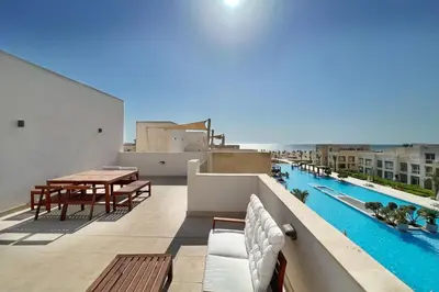 a balcony with a table and chairs and a swimming pool at Dazzling 2 BDR w Rooftop Mangroovy Free Pool & Beach Access in Hurghada
