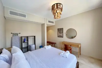 a bedroom with a white bed and a mirror at Dazzling 2 BDR w Rooftop Mangroovy Free Pool & Beach Access in Hurghada