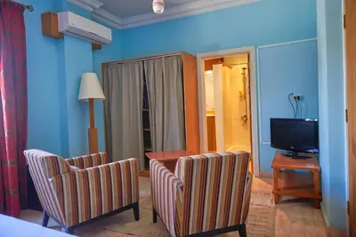 a living room with two chairs and a television at Sweet Rooms in Luxor