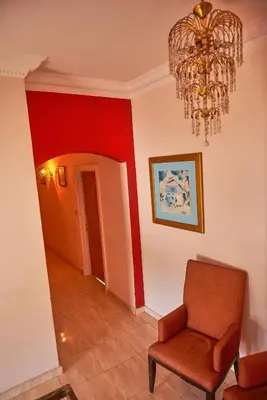 a living room with a chair and a chandelier at Sweet Rooms in Luxor