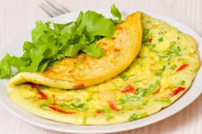 a white plate with an omelet and lettuce on a plate at Sweet Rooms in Luxor