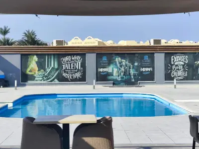 a swimming pool with a table and chairs in front of a building at Scandic Resort Apartments in Hurghada