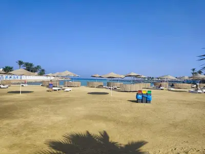 a beach with umbrellas and chairs and the ocean at Scandic Resort Apartments in Hurghada