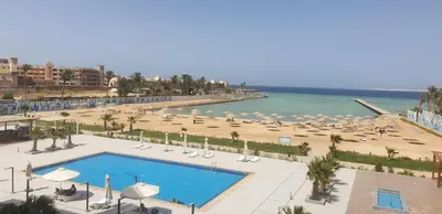 a view of a beach with a pool and chairs and umbrellas at Scandic Resort Apartments in Hurghada