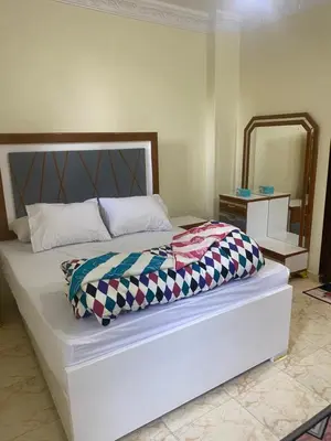 a bedroom with a large white bed with a mirror at Sunrise shiny Nubian Guest House in Aswan