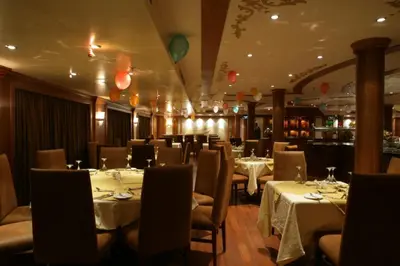 a restaurant with white tables and chairs and a bar at Nile Cruise 3 nights From Aswan to Luxor Every Friday, Monday and Wednesday with tours in Jazīrat al ‘Awwāmīyah