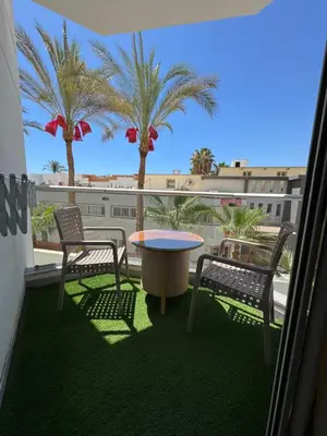 a balcony with two chairs and a table and palm trees at Scandic Rezort in Hurghada
