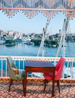 a table and chairs on a balcony with a view of the water at Kana Kato in Aswan