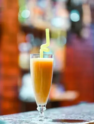a glass of orange juice with a yellow straw at Kana Kato in Aswan