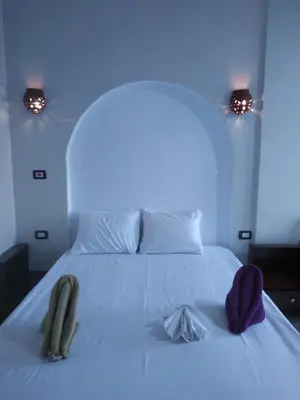 a bedroom with a white bed with two slippers on it at Kana Kato in Aswan