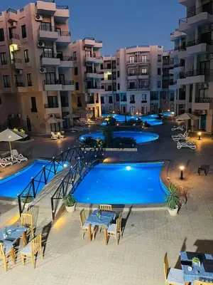 a swimming pool with tables and chairs in front of a building at Tropical 1 bed apartment in Hurghada