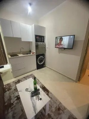 a small kitchen with a table and a tv on the wall at Tropical 1 bed apartment in Hurghada