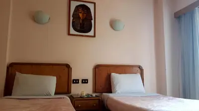 a bedroom with two beds and a picture on the wall at New Pola Hotel in Luxor