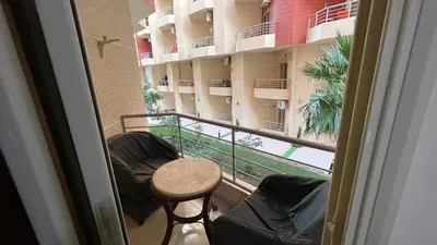 a balcony with two chairs and a table and a building at Casablanca beach resort, first line, with private beach and swimming pools,hurghada in Hurghada