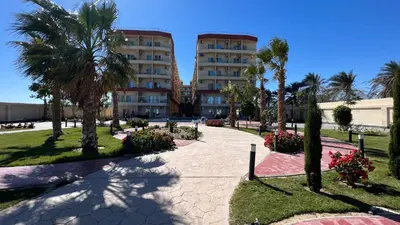 a walkway in front of a building with palm trees at Casablanca beach resort, first line, with private beach and swimming pools,hurghada in Hurghada
