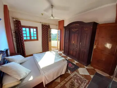 a bedroom with a bed and a wooden cabinet at Lucky House in Luxor