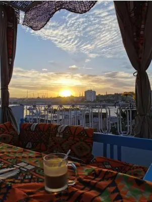 a drink on a table with a view of a boat at Gamal Robob Nubian Guest House in Aswan