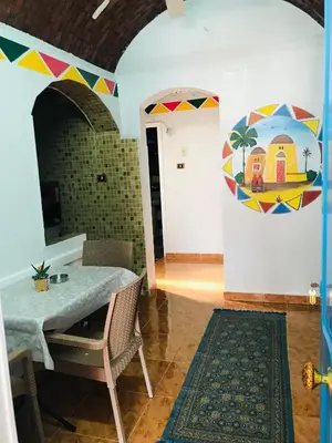 a dining room with a table and a painting on the wall at Gamal Robob Nubian Guest House in Aswan