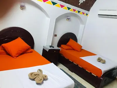 two beds in a room with orange and white at Gamal Robob Nubian Guest House in Aswan