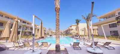 a pool with chairs and palm trees in a resort at Modern 1-Bedroom Apartment in G-Cribs, El Gouna, pool access in Hurghada