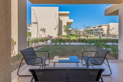 two chairs and a table on a patio with a yard at Modern 1-Bedroom Apartment in G-Cribs, El Gouna, pool access in Hurghada