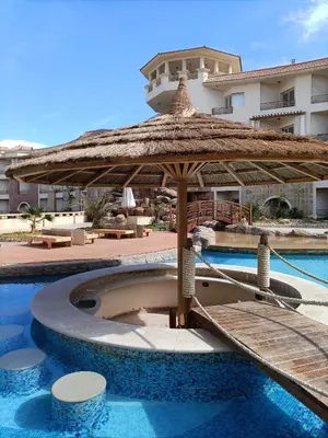 a swimming pool with a umbrella and a resort at Tony's Privy Beds by Red Sea in Hurghada