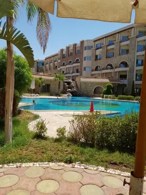 a swimming pool in front of a large building at Tony's Privy Beds by Red Sea in Hurghada