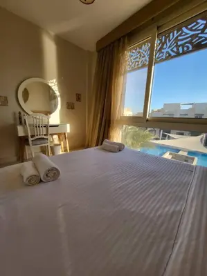 a bedroom with a large bed and a large window at Mangroovy - 2BR Marvelous Pool View Apartment in Hurghada