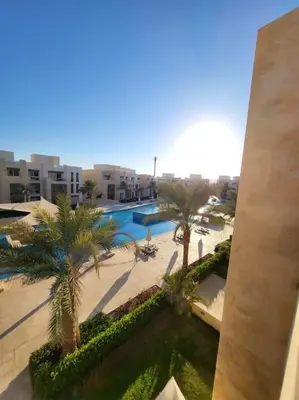a view of a resort with a pool and palm trees at Mangroovy - 2BR Marvelous Pool View Apartment in Hurghada