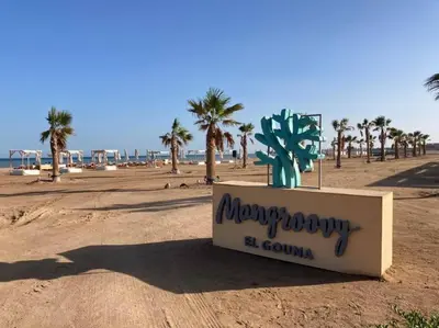 a sign on the beach with palm trees in the background at Mangroovy - 2BR Marvelous Pool View Apartment in Hurghada