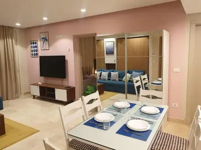 a dining room and living room with a table and chairs at Mangroovy - 1BR GF +2 wall beds Garden & Pool view in Hurghada