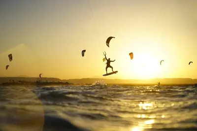 a person on a surfboard in the water with kites at Mangroovy - 1BR Ravishing Lake and Mountain View in Hurghada