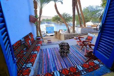 a patio with chairs and a rug with a view of the water at Nubian studio in Aswan